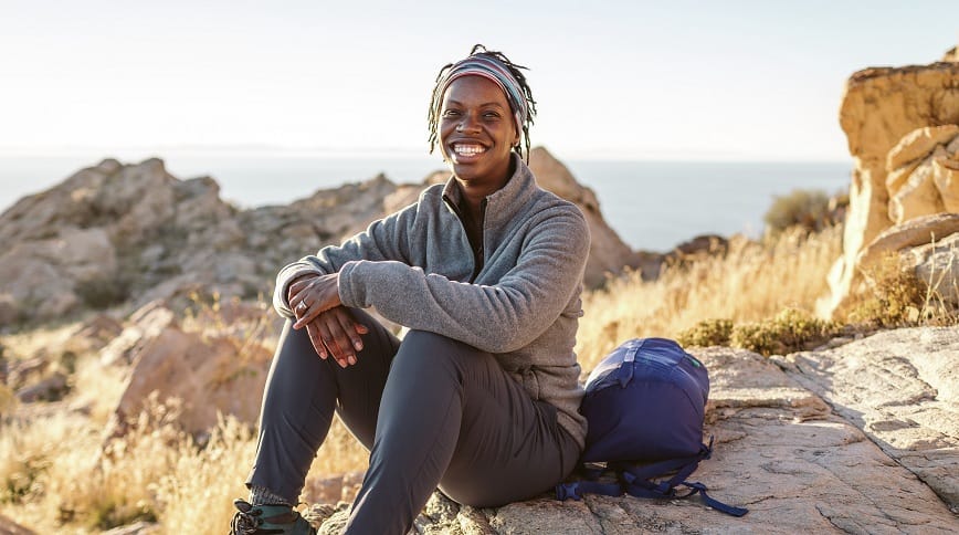 Black woman sits on a rock on a hike